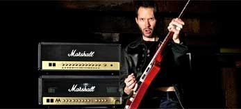 man playing guitar next to amp